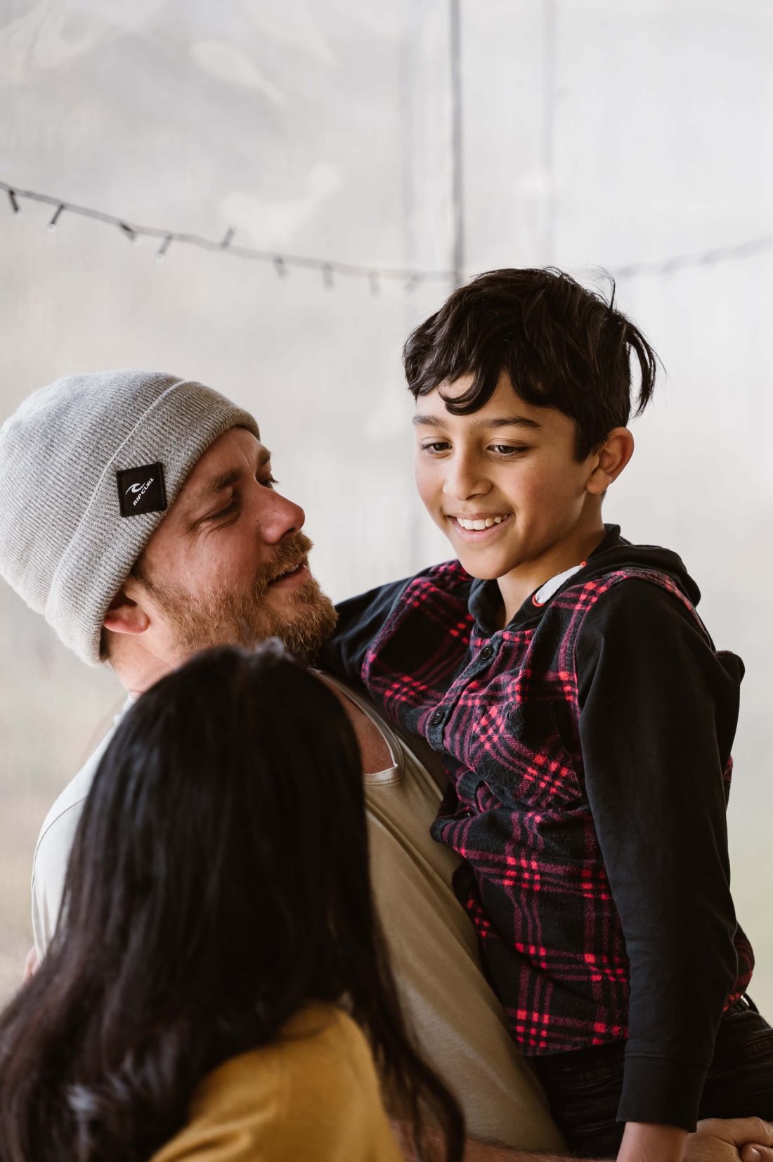 Boy being held up by his father and looking at his mother. Father and son smiling